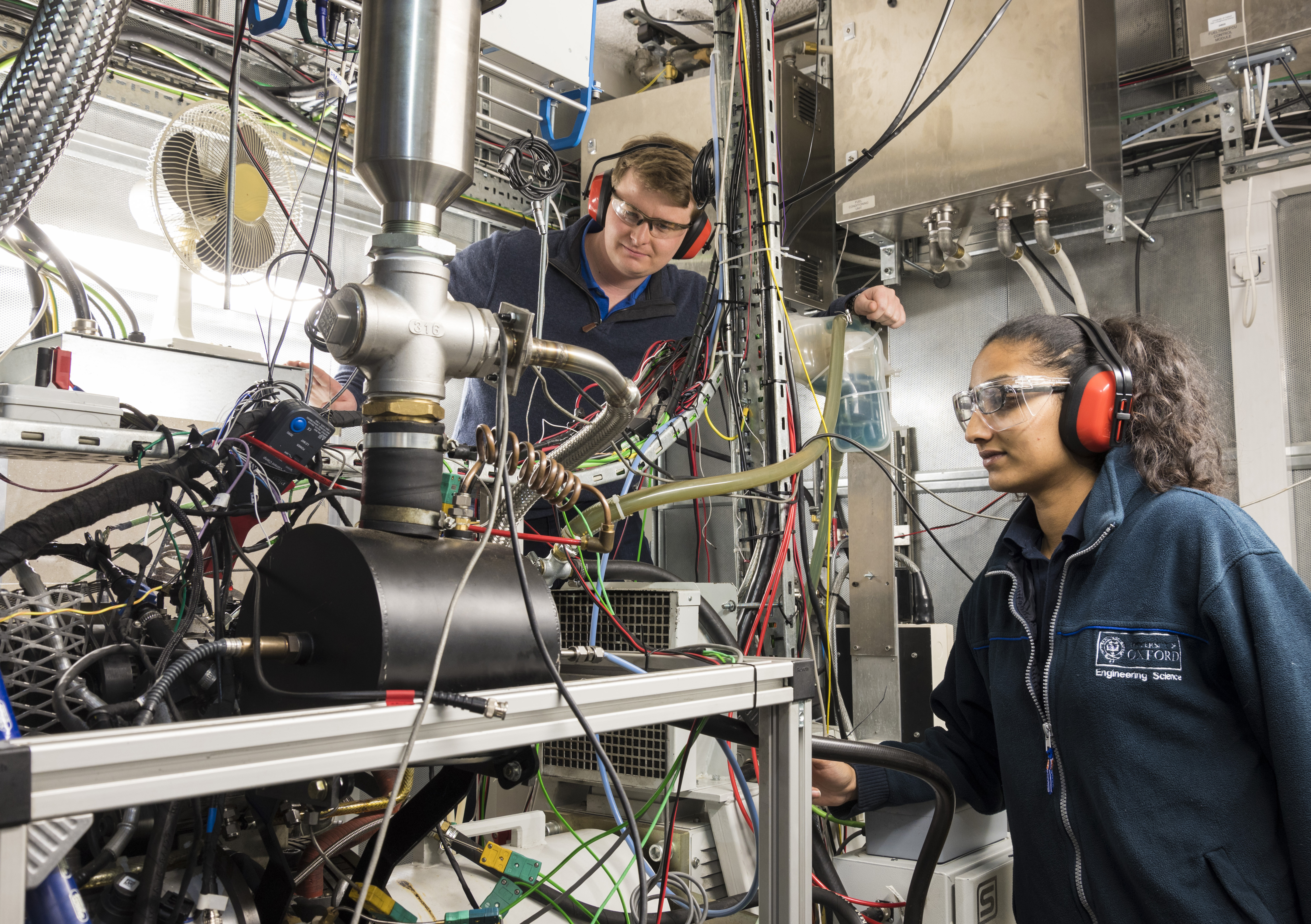 Students wearing safety gear looking at a big machine